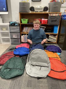 Student sits with backpacks