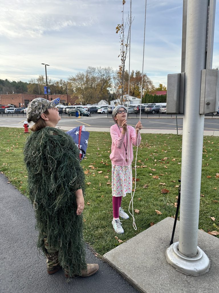 two students look up at a flag pole