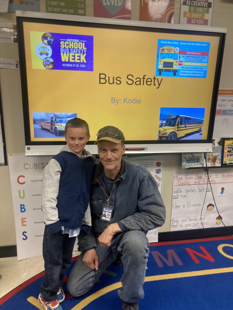 A bus driver sits with a student