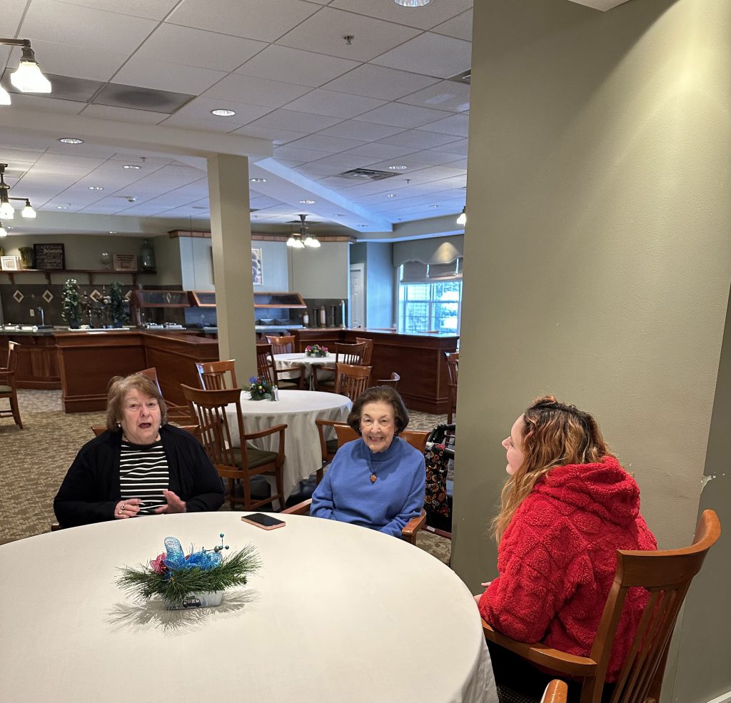 student sits at table with seniors