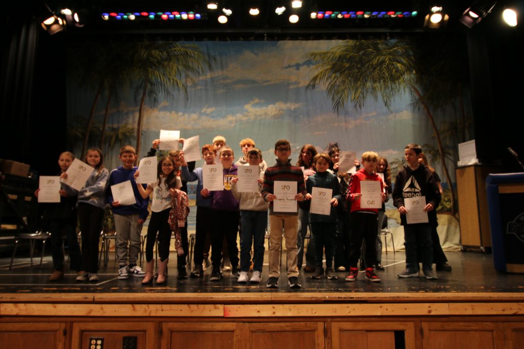 Spelling bee participants stand on stage